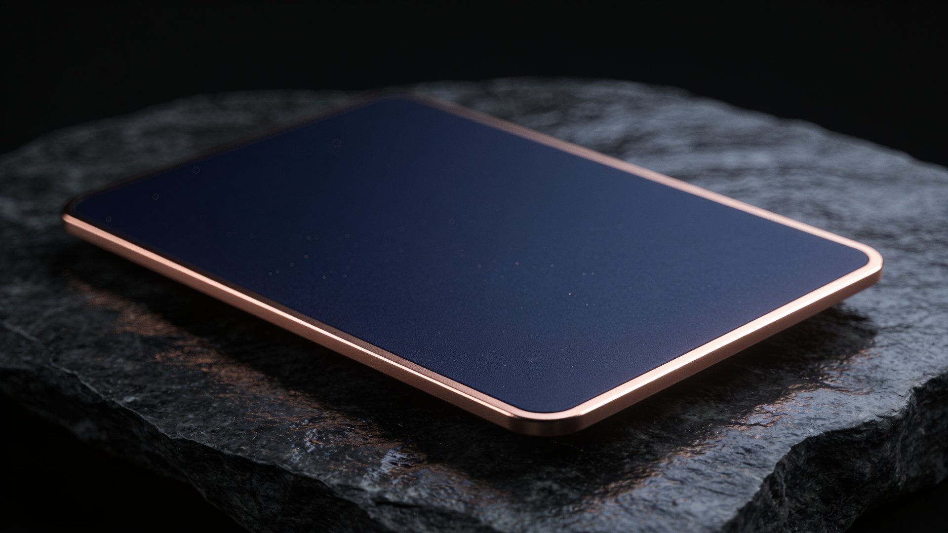 The card resting on dark stone — a deep navy face with a rose-gold edge catching the light